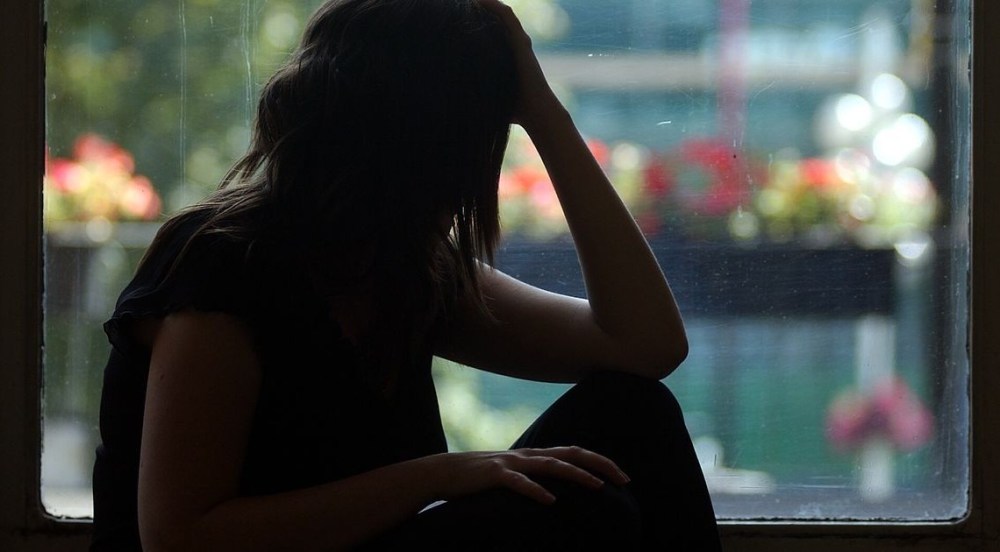 The silhouette of a woman holding her head.