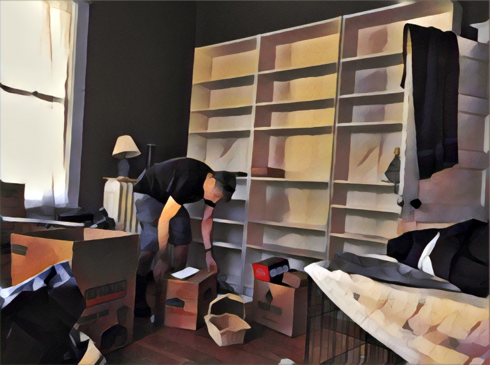 Guy packing a box in front of empty bookcases.